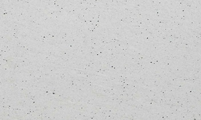 Close-up of a white speckled surface with small black dots scattered throughout.